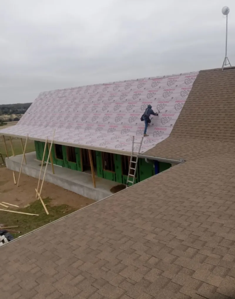 Worker preparing underlayment for a metal roof installation in Sodus